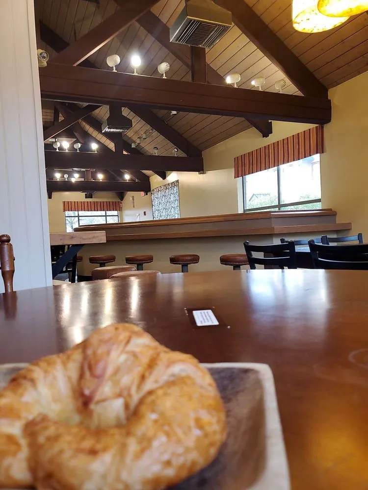 A croissant at a long wooden table in the bright upstairs room